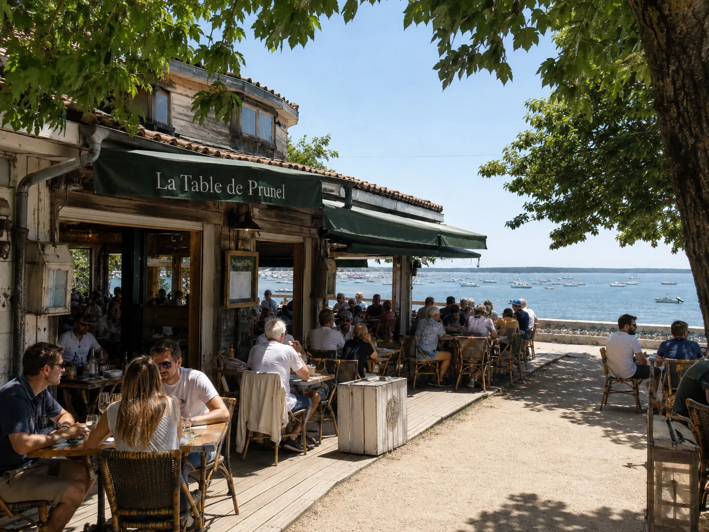 Terrasse en bois du restaurant face au bassin, bateaux au mouillage